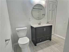 bathroom featuring toilet, baseboards, and vanity