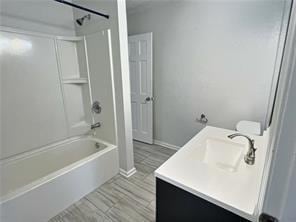 bathroom featuring tub / shower combination, vanity, and baseboards