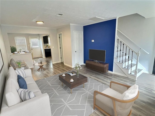 living room with stairs, wood finished floors, visible vents, and baseboards