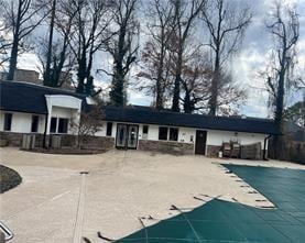 rear view of property with a patio area, driveway, and a community pool