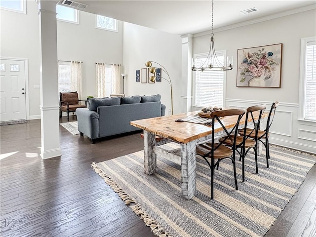 dining area featuring a healthy amount of sunlight, dark hardwood / wood-style floors, a chandelier, and decorative columns