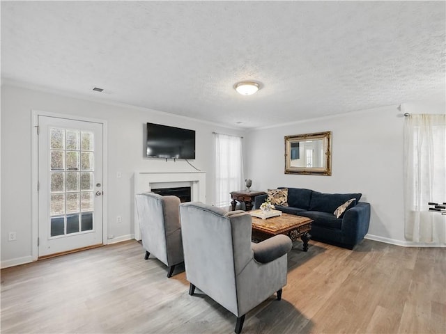 living area with light wood-style floors, a wealth of natural light, and a fireplace