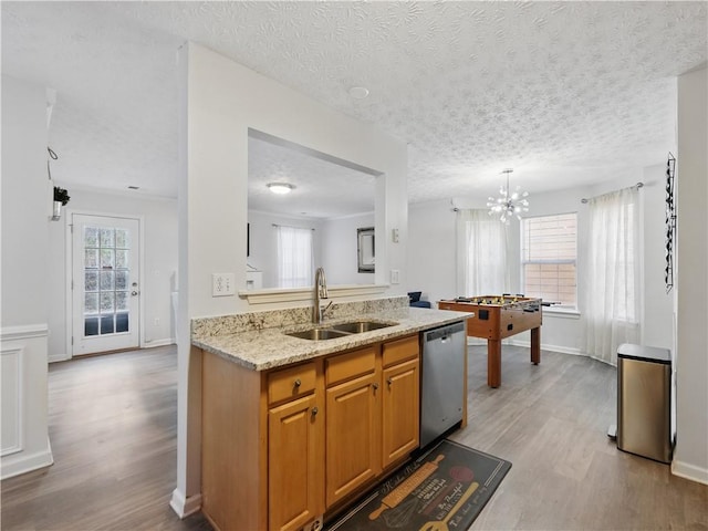 kitchen featuring dishwasher, wood finished floors, a sink, and light stone countertops