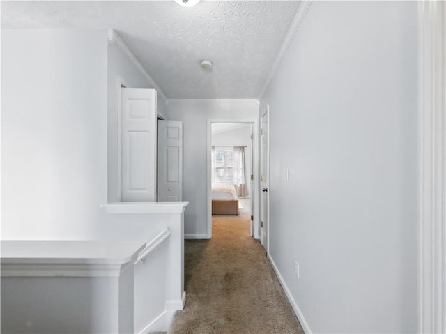 hallway featuring crown molding, a textured ceiling, baseboards, and carpet flooring