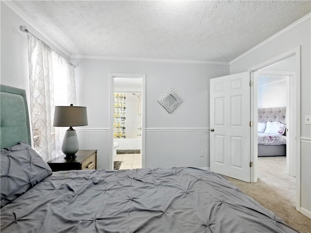 carpeted bedroom with a textured ceiling, ornamental molding, and ensuite bathroom