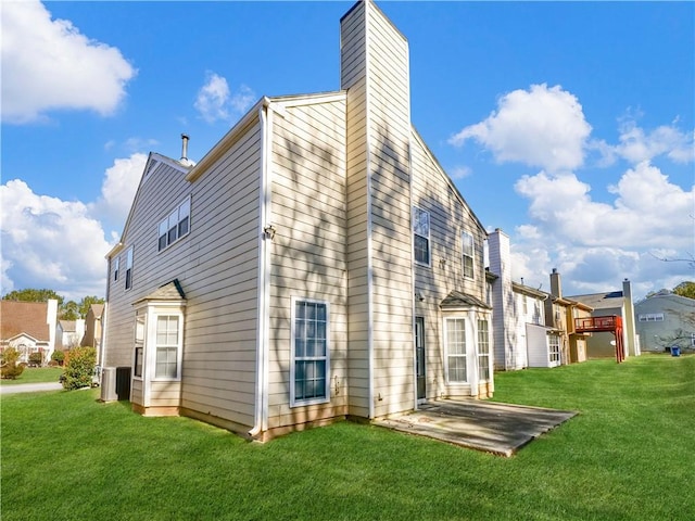 back of house featuring a yard, a chimney, and a patio area