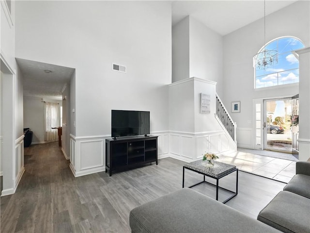 living area with a wainscoted wall, visible vents, a decorative wall, wood finished floors, and stairs