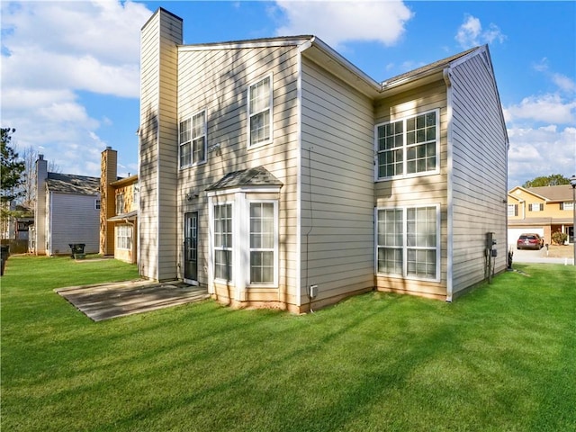 rear view of property with a patio area, a lawn, and a chimney