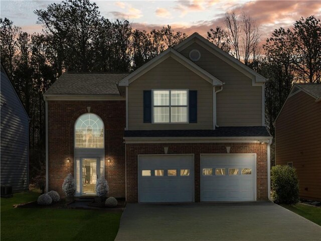 traditional home featuring brick siding, a yard, driveway, and an attached garage