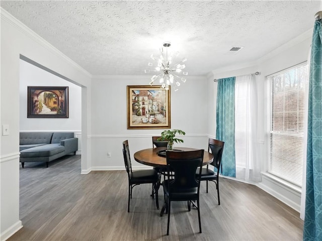 dining room with ornamental molding, wood finished floors, visible vents, and a notable chandelier