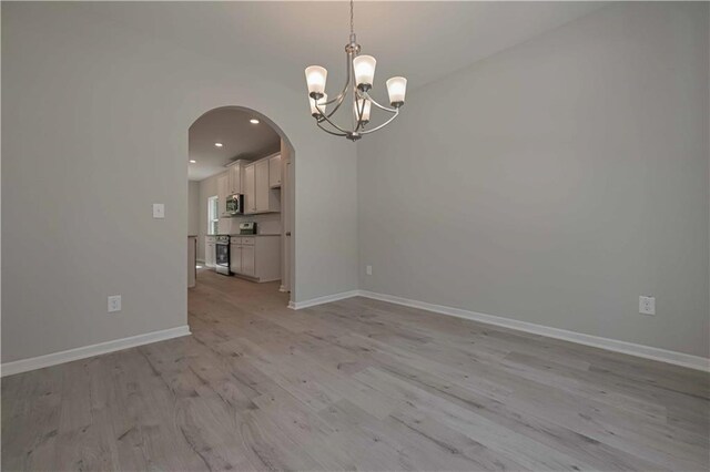 empty room featuring a chandelier and light hardwood / wood-style floors