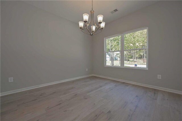 unfurnished room featuring light hardwood / wood-style flooring and an inviting chandelier