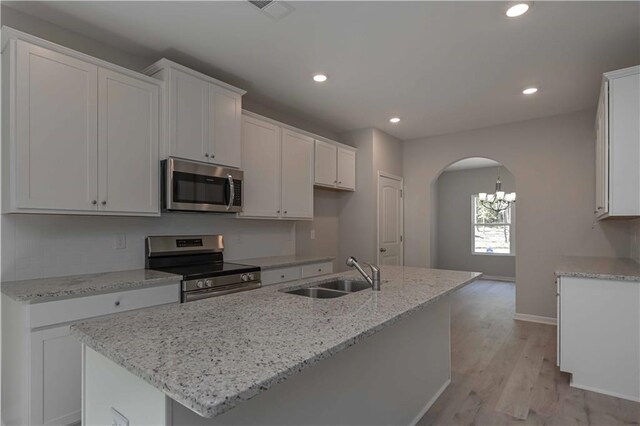 kitchen featuring sink, light hardwood / wood-style floors, a center island with sink, white cabinets, and appliances with stainless steel finishes