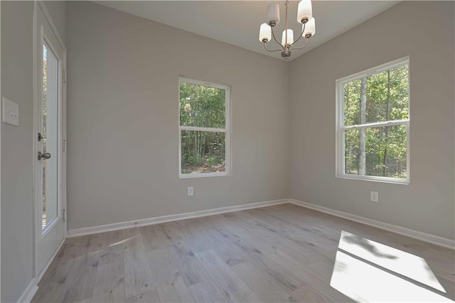 spare room with a chandelier and light hardwood / wood-style flooring