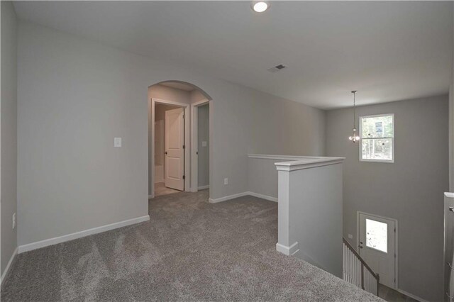 unfurnished room with carpet floors and a chandelier