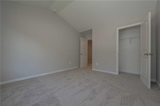 unfurnished bedroom featuring light carpet, a closet, and vaulted ceiling