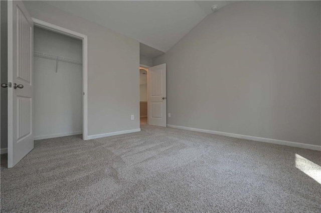 unfurnished bedroom featuring carpet flooring, lofted ceiling, and a closet