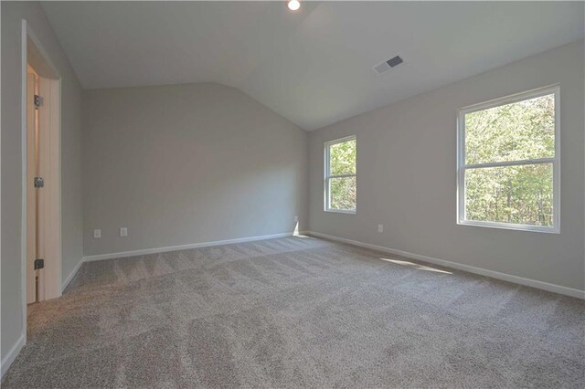 carpeted spare room featuring lofted ceiling