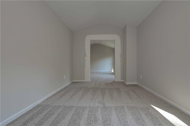 spare room featuring light carpet and lofted ceiling