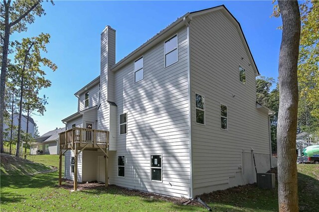 rear view of property with a yard, a deck, and cooling unit