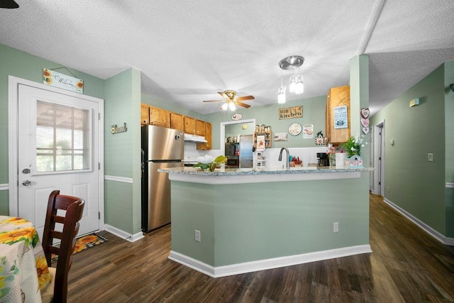 225 Hardin Rd SW, Plainville, GA 30733 - kitchen featuring freestanding refrigerator, ceiling fan, under cabinet range hood, dark wood-style flooring, and brown cabinets