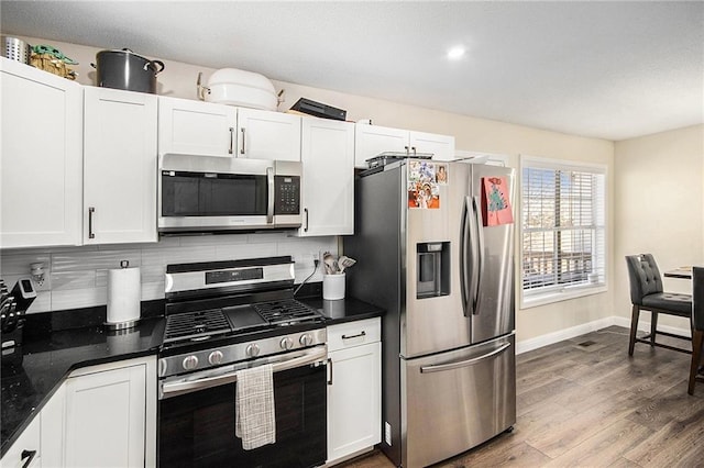 kitchen with dark countertops, appliances with stainless steel finishes, decorative backsplash, and white cabinetry