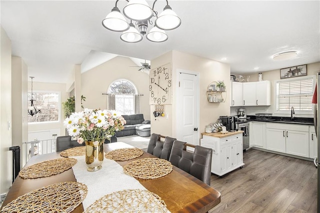 dining space with ceiling fan with notable chandelier, dark wood-type flooring, and plenty of natural light