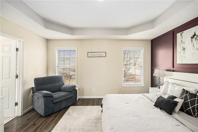 bedroom with a raised ceiling, baseboards, and dark wood finished floors