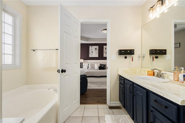 bathroom featuring tile patterned flooring, a healthy amount of sunlight, connected bathroom, and a garden tub