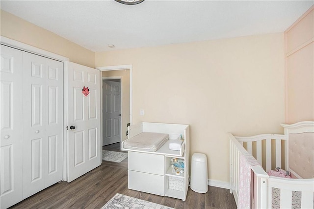bedroom featuring baseboards, dark wood finished floors, and a closet