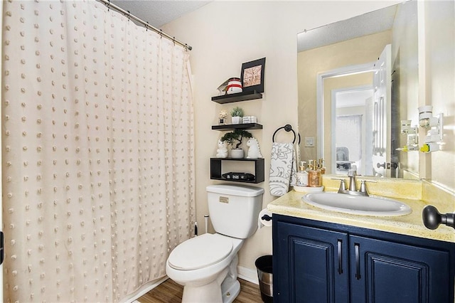 bathroom featuring toilet, curtained shower, wood finished floors, and vanity