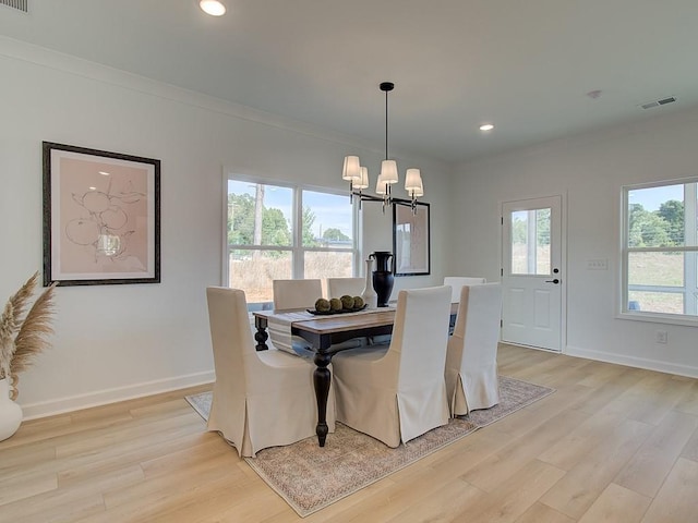 dining space featuring a notable chandelier, crown molding, and light hardwood / wood-style flooring