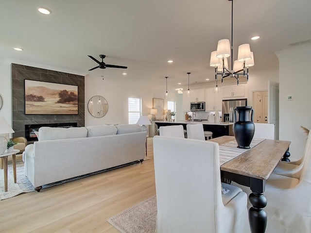 dining area with light hardwood / wood-style flooring, a tile fireplace, and ceiling fan