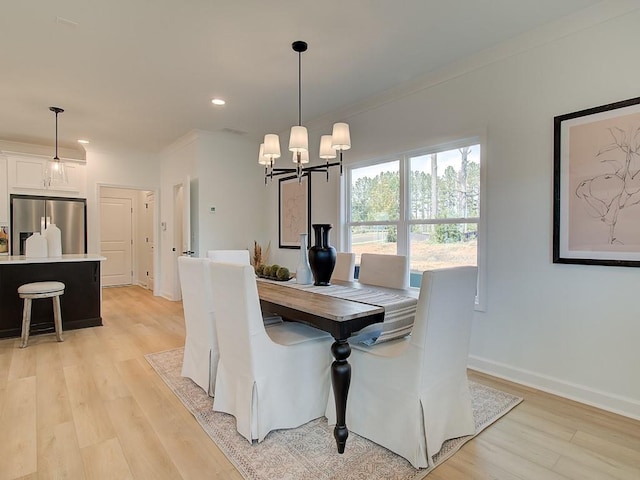 dining room featuring ornamental molding, a notable chandelier, and light hardwood / wood-style flooring