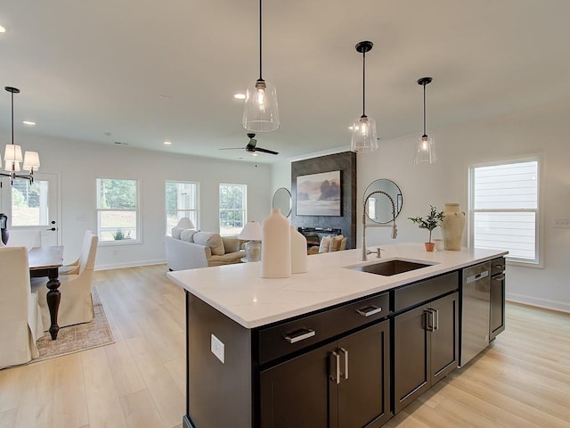 kitchen with pendant lighting, stainless steel dishwasher, sink, and an island with sink