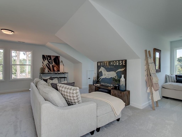 living room featuring vaulted ceiling, light colored carpet, and a healthy amount of sunlight