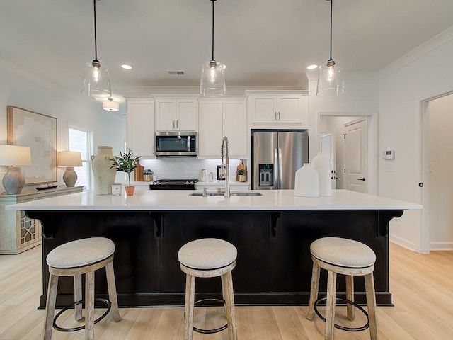 kitchen featuring white cabinetry, appliances with stainless steel finishes, sink, and a large island with sink