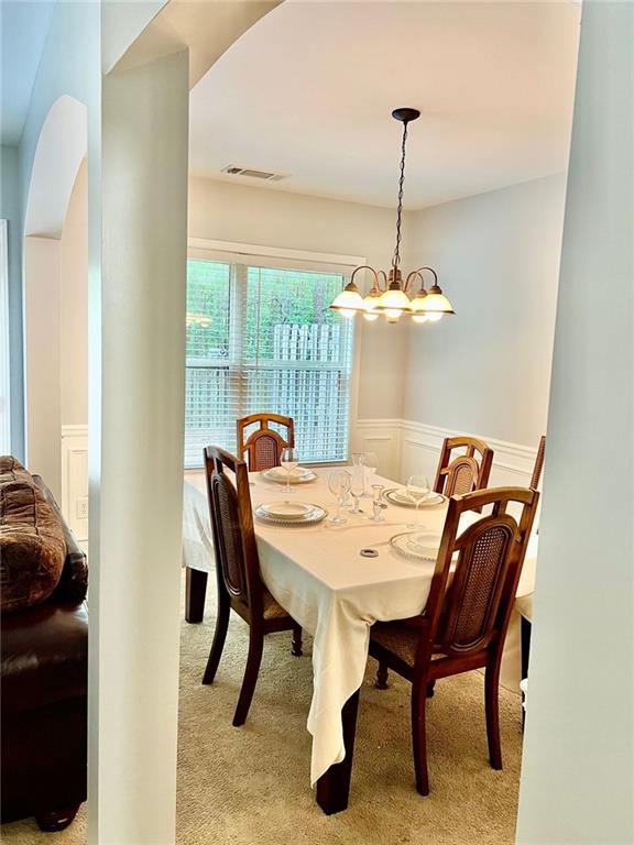 2691 Pointcrest Way, Grayson, GA 30017 - dining space featuring light carpet, wainscoting, a chandelier, and a decorative wall