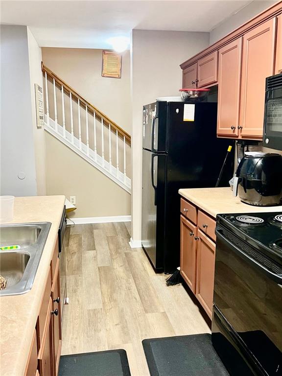 2691 Pointcrest Way, Grayson, GA 30017 - kitchen with black appliances, light wood finished floors, light countertops, and brown cabinetry