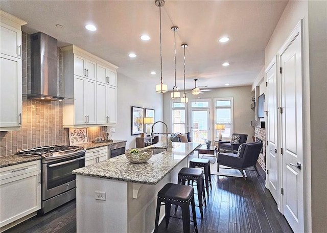 4107 Township Pkwy Unit 69, Sandy Springs, GA 30342 - kitchen with wall chimney range hood, stainless steel gas stove, recessed lighting, an island with sink, and backsplash
