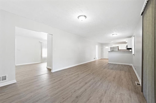 unfurnished living room with wood-type flooring and a textured ceiling