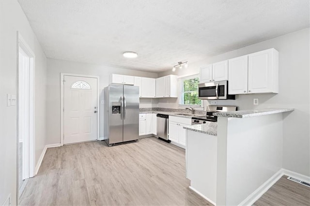 kitchen with sink, light hardwood / wood-style flooring, stainless steel appliances, white cabinets, and kitchen peninsula