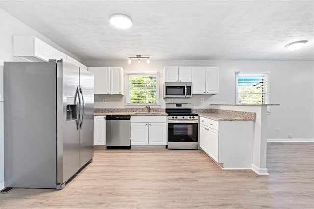 kitchen with sink, white cabinets, light hardwood / wood-style floors, stainless steel appliances, and a textured ceiling