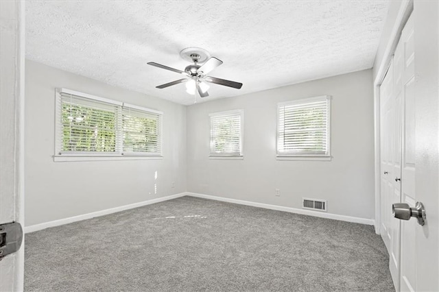 empty room with ceiling fan, light carpet, and a textured ceiling