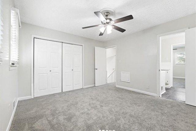 unfurnished bedroom featuring ceiling fan, carpet floors, a closet, and a textured ceiling