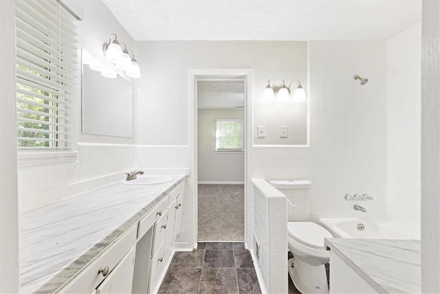 full bathroom with washtub / shower combination, tile walls, vanity, a textured ceiling, and toilet