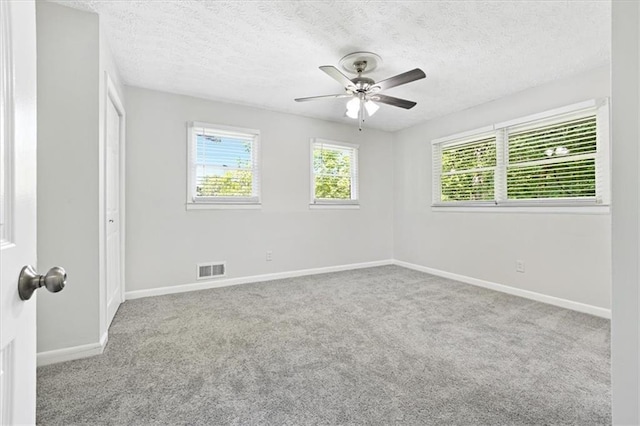 spare room with ceiling fan, light colored carpet, and a textured ceiling