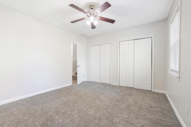 unfurnished bedroom featuring multiple closets, carpet, and ceiling fan