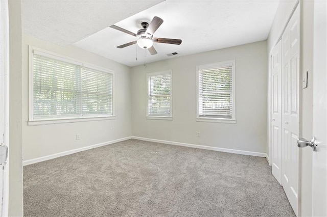 carpeted spare room with a textured ceiling and ceiling fan