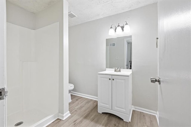 bathroom featuring toilet, a shower, a textured ceiling, vanity, and hardwood / wood-style flooring